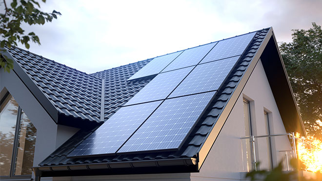 Solar panels installed on the roof of a residential home with sunlight shining in the background.