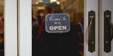 A glass door with an Open sign hanging on it.