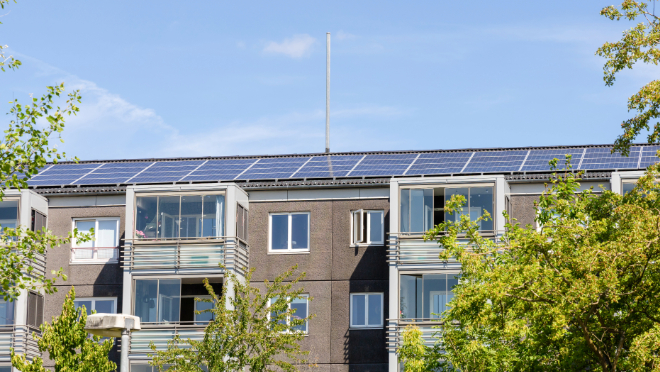 A solar panel array on the roof of a building with the sky in the background A solar panel array on the roof of a building with the sky in the background
