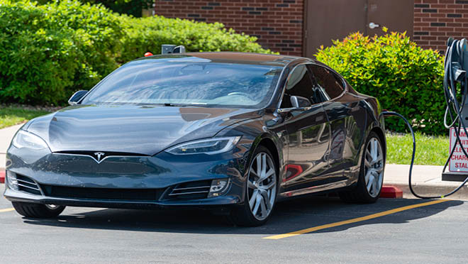 Tesla electric car charging in a parking lot. Tesla electric car charging in a parking lot.